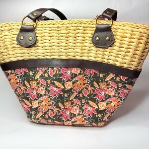 Straw tote bag with floral print, featuring brown leather trim and straps: